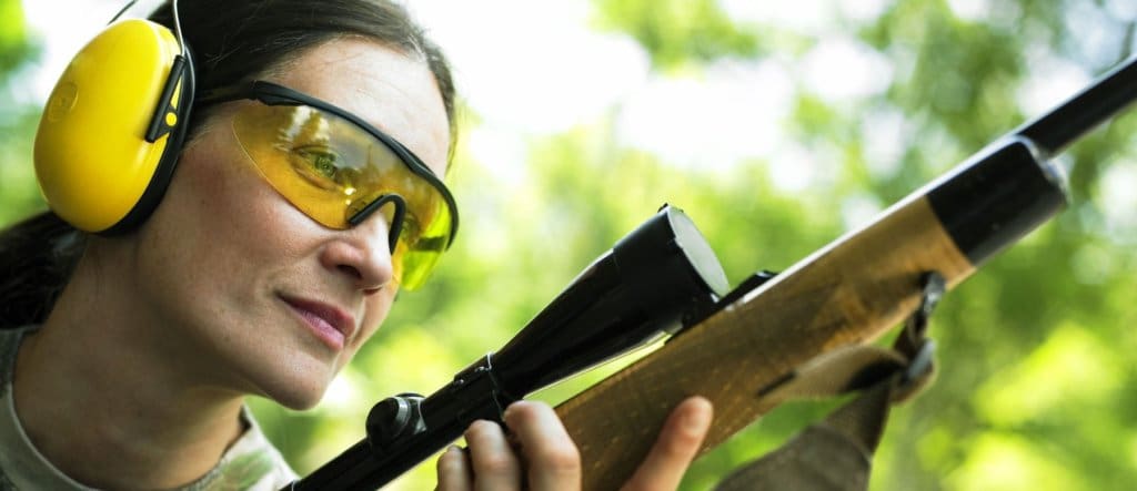 Woman with ear and eye protection holding a gun