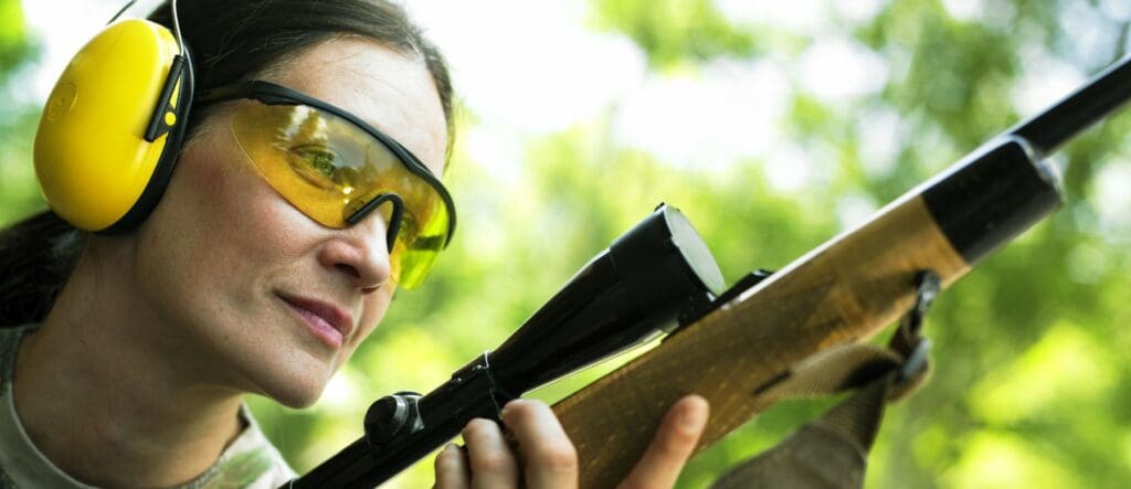 Woman with ear and eye protection holding a rifle to illustrate best rifles for women.
