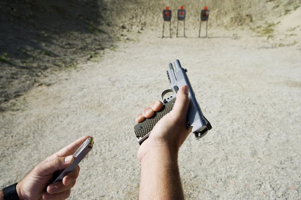 a man reloads a gun at a shooting range with targets in the background to illustrate How To Dispose Of Ammunition
